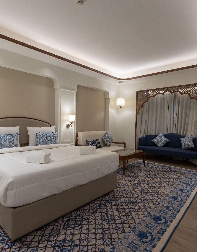 Corner view shot of the Mandakini Room featuring a plush double bed along with a long patterned carpet on the floor at Bhagirathi by RDB Atishay.