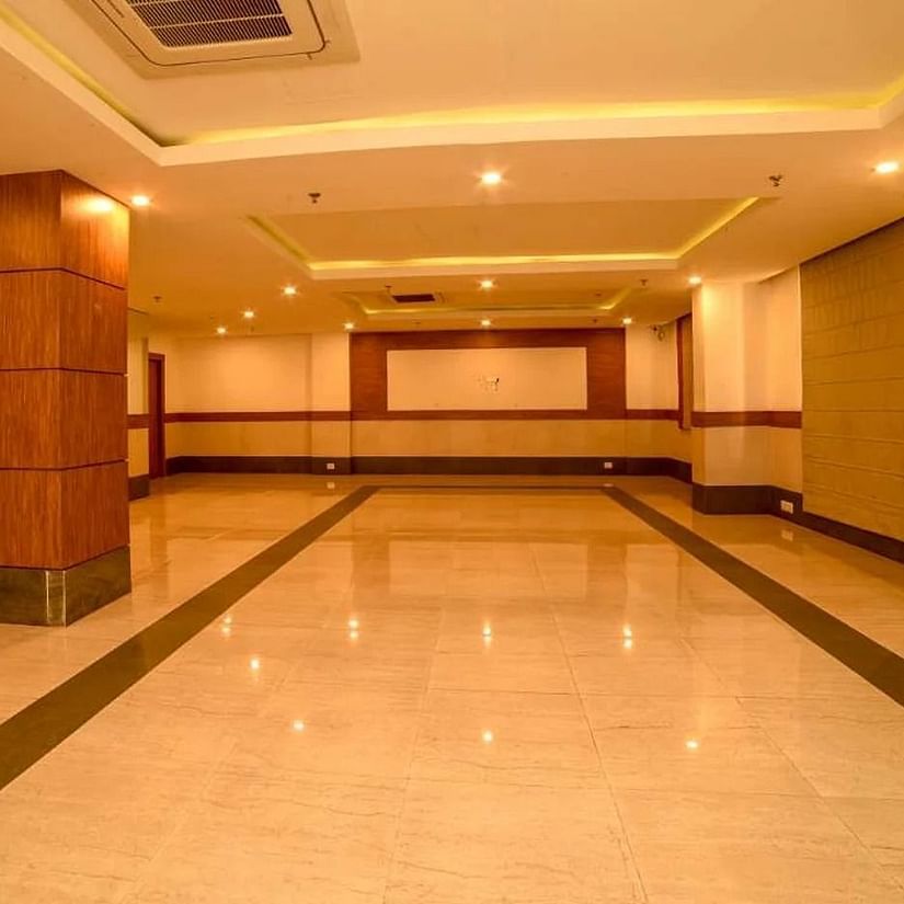 An image of a spacious banquet hall with installed lights in the ceiling - An image of a reception lobby featuring a reception desk , and a seating area for the guest - Max Hotel Jabalpur