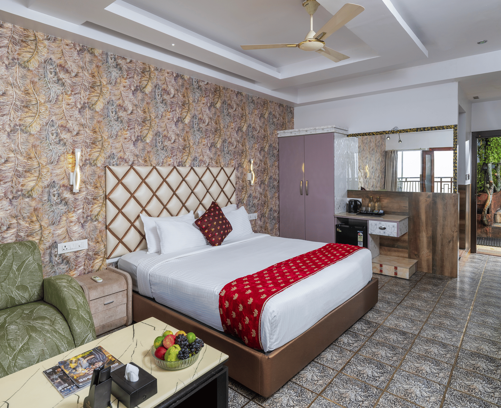 A bedroom of the Premium Club Suite at Parakkat Nature Hotel and Resorts, Munnar, featuring a large bed with decorative textiles, a ceiling fan, wood accents, and large windows opening onto outdoor greenery.