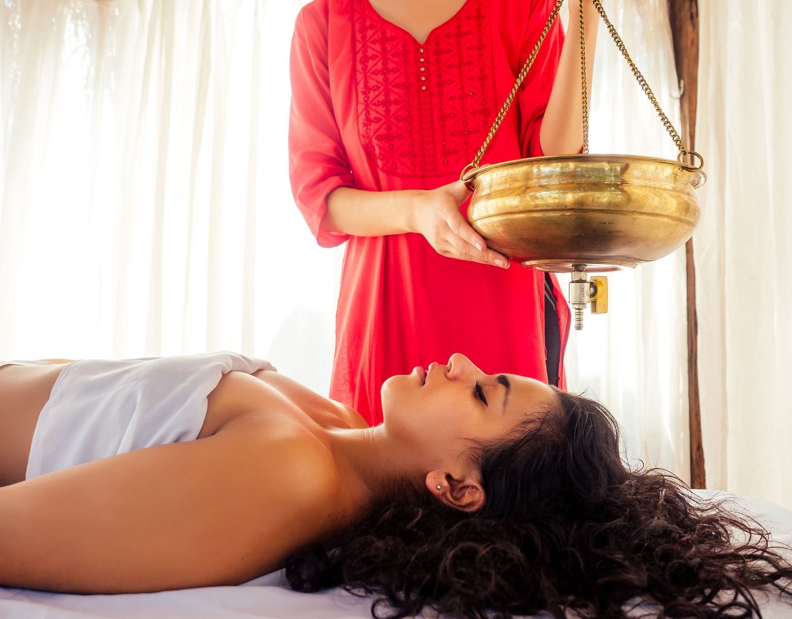 Woman receiving an Ayurvedic oil treatment on her forehead.
