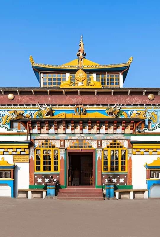 Colourful Buddhist monastery with ornate golden details, standing against a clear blue sky.