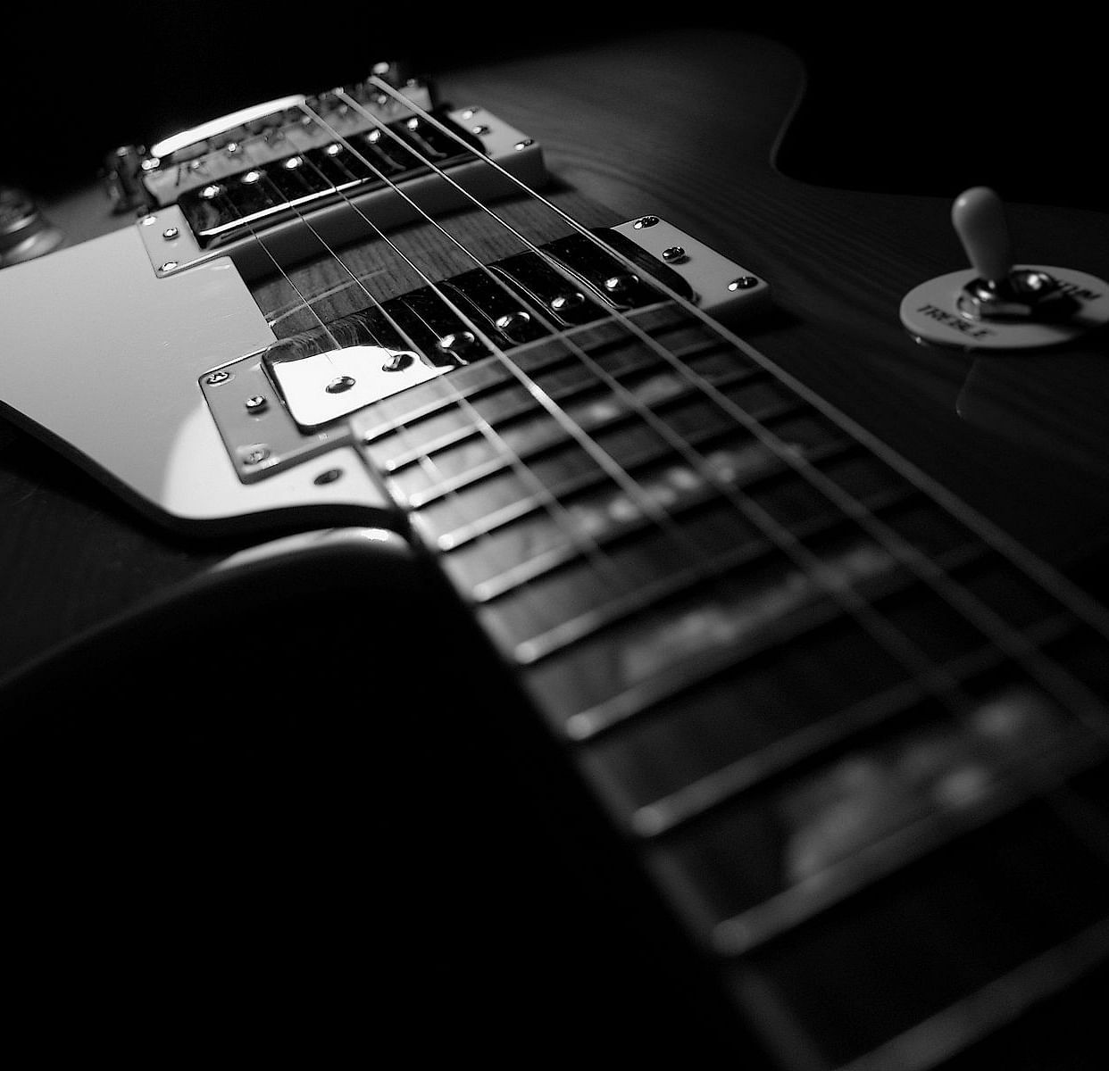 An image of a guitar where partially a beam of light is settled