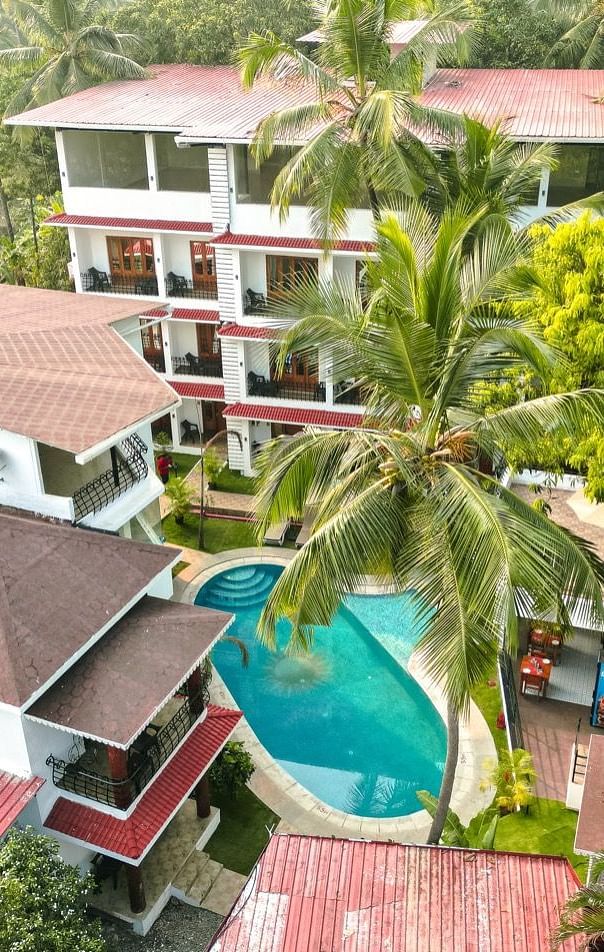An aerial view of the The Verda de Miranda Resort nestled amidst palm trees, featuring multiple buildings and a turquoise pool.