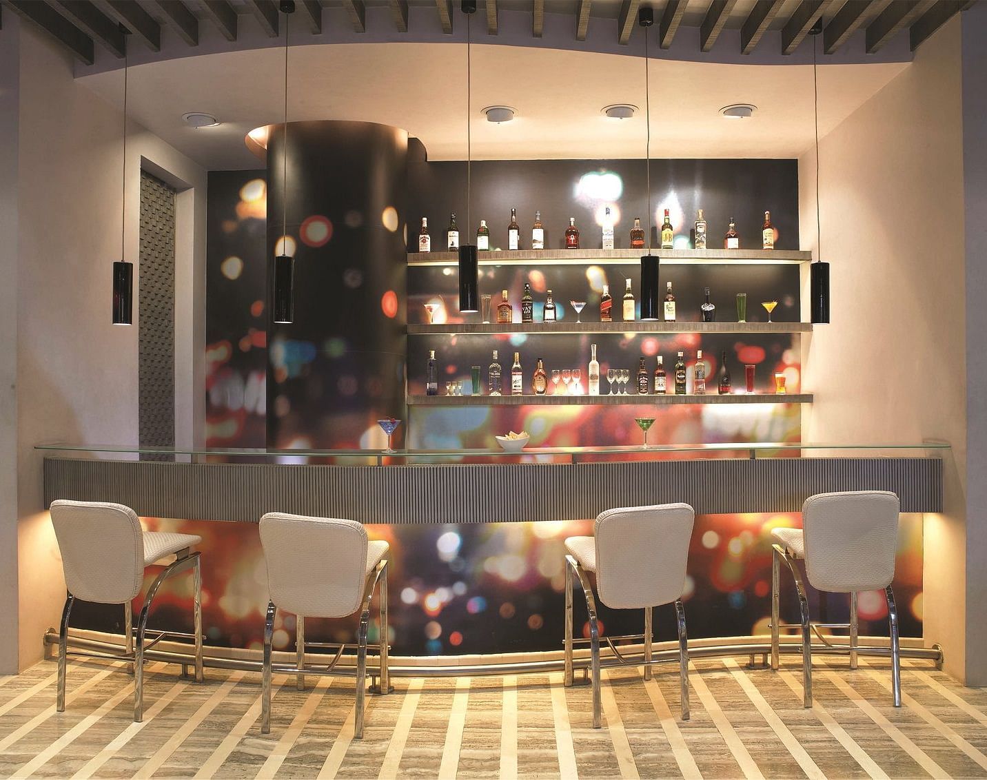 Image of zebra lounge at our hotel featuring a bar stand with chairs and bottles of alcohol | Mirage Hotel