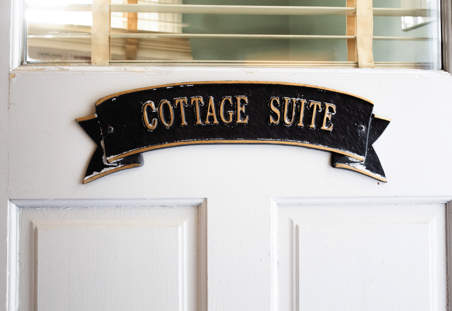 A white door with a black sign that reads 'COTTAGE SUITE' in gold lettering.