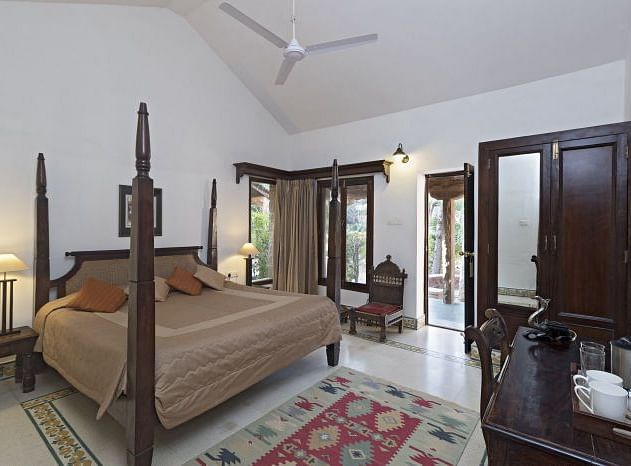 An image of a room with a bed, bed side table, lamp, work desk and chair, ceiling fan and other decorative items - MANVAR Resort & Desert Camp