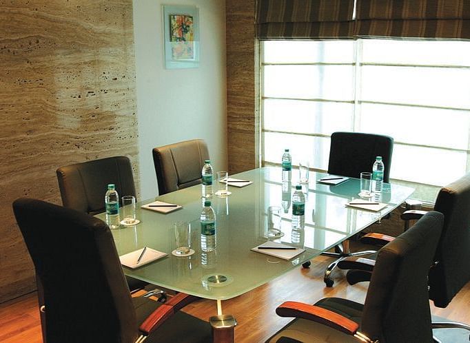 Image of a meeting room at our hotel featuring a glass table with seven chairs around it. | Mirage Hotel