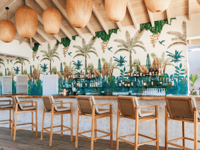 A stylish outdoor bar area with high stools is decorated with balloons and overlooks a bright, inviting space.