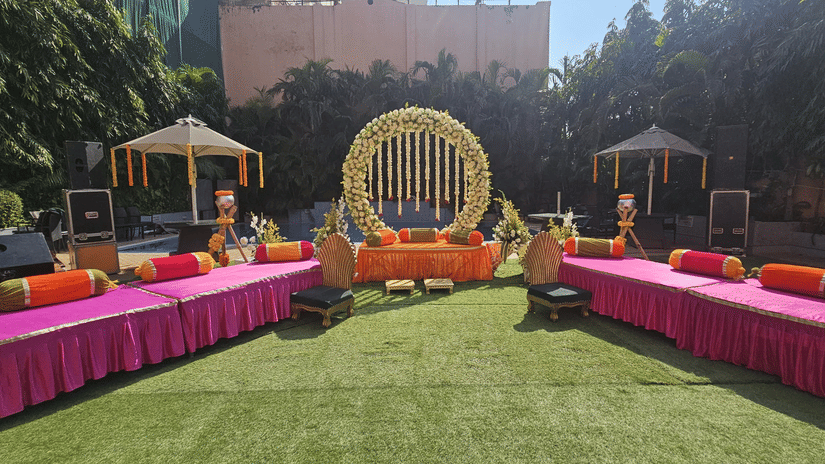 A wide view of an outdoor lawn area with pink draped tables and floral decorations | HHI Varanasi