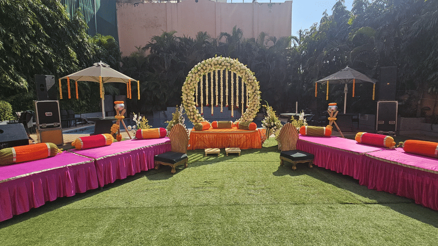 A wide view of an outdoor lawn area with pink draped tables and floral decorations | HHI Varanasi