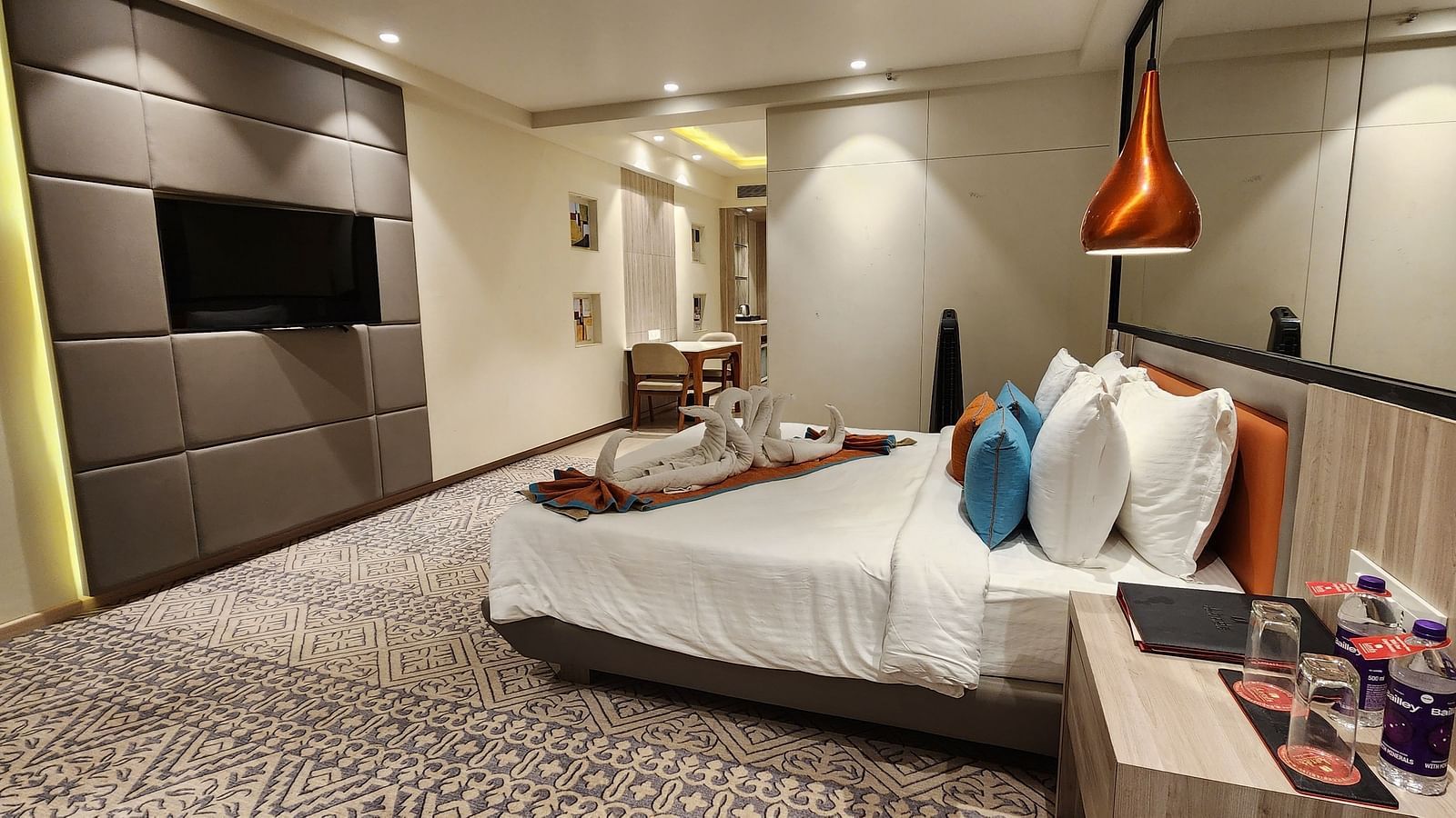 Elegant hotel room with a king-sized bed, bedside tables, modern wall art, and a mounted flat-screen TV.