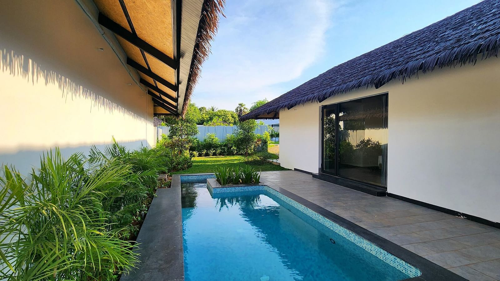 A serene swimming pool lined with green plants in the corner at the Exotic Pool Villa at The Shore, Trishvam.