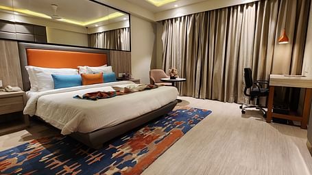 Contemporary room with bright decor, patterned carpet, and a bed facing a flat-screen television.