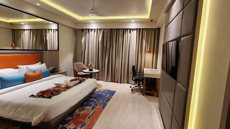 Elegant bedroom with full-length curtains, bedside tables, and a bed adorned with blue and orange cushions.