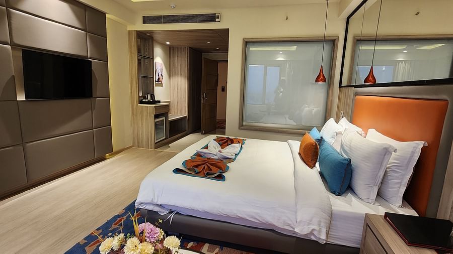 Stylish hotel room with wooden accents, a comfortable bed, and a clear view of the glass-panelled bathroom.