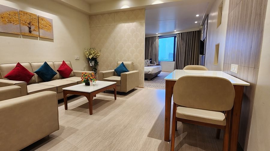 Bright and airy hotel lounge with beige furniture, red and blue cushions, and a coffee table.