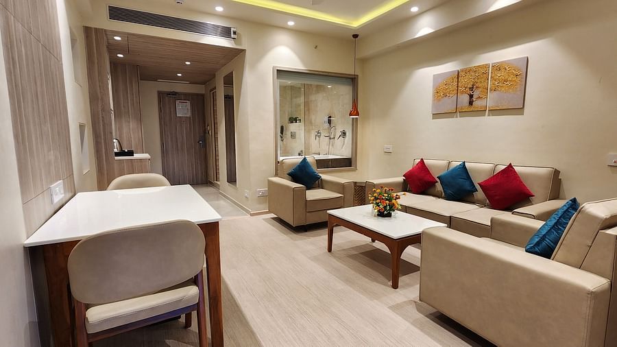 Spacious hotel suite with a work desk, comfortable seating area, and warm ambient lighting.