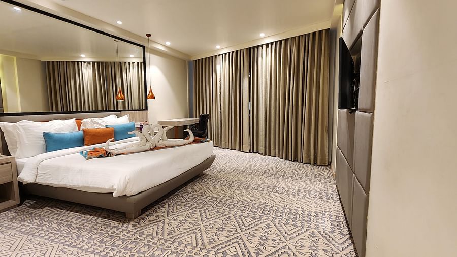 Luxurious bedroom with a large double bed, mirrored wardrobe, floor-to-ceiling curtains, and soft lighting.