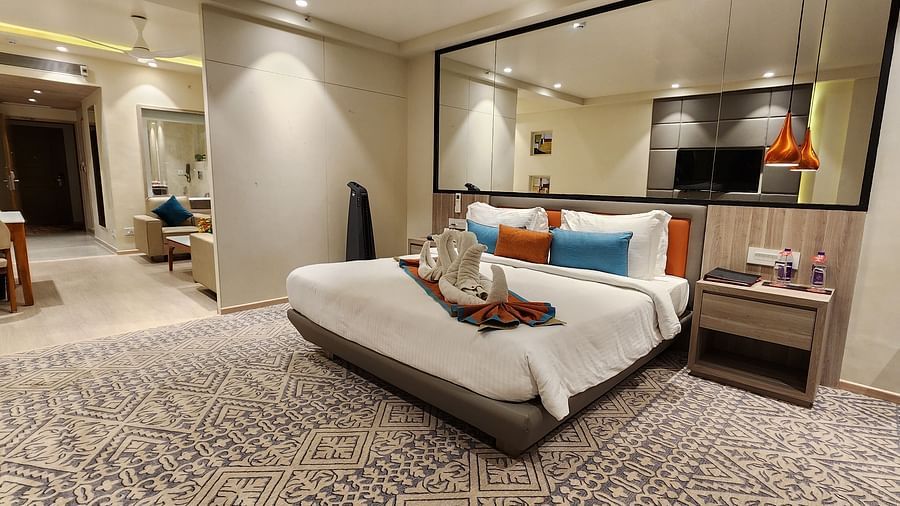 Luxurious bedroom with a king-sized bed, reading lamps, and wall-length mirror in a calm setting.