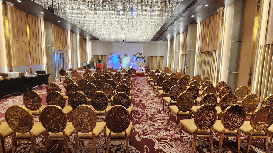 a banquet hall at Lords Inn Rajkot with theatre style seating arrangement with a buffet counter on side and a small stage area decorated at the front