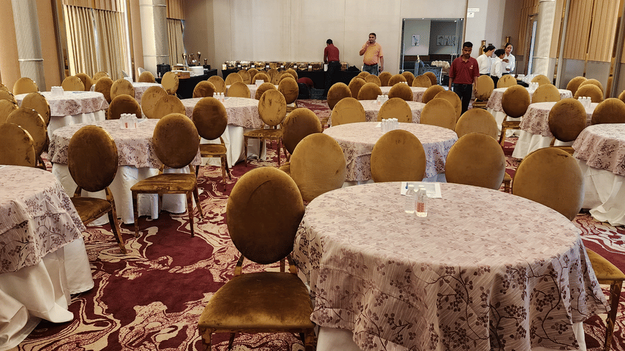 a closeup shot of a banquet hall in Lords Inn Rajkot with cluster seating arrangement and a buffet counter at the back