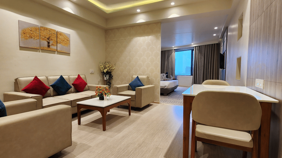 duplicate of a different angle shot of the lounge area at a semi-suite room at Lords Inn Rajkot with ample of seating area, a bed, and a ceiling-to-floor windows 