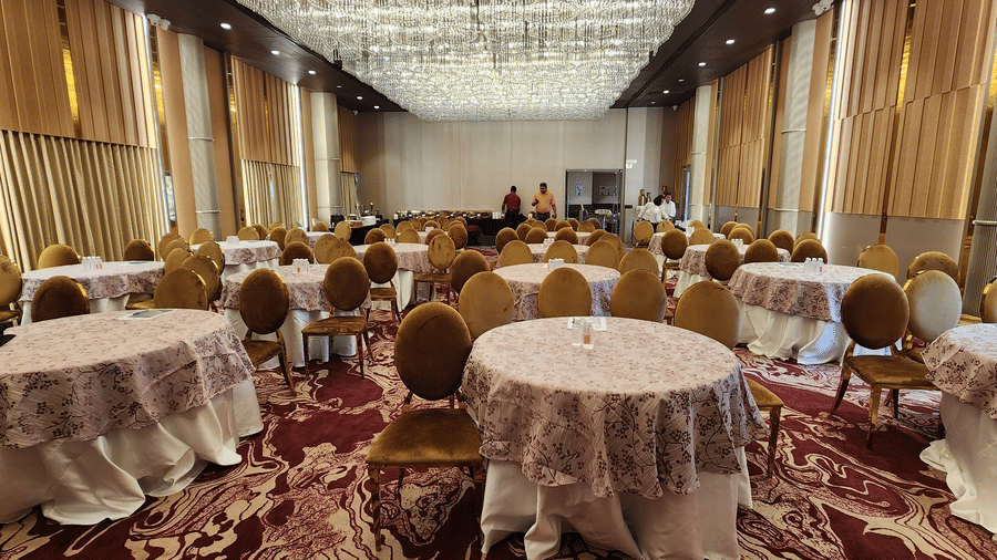a banquet hall in Lords Inn Rajkot with cluster seating arrangement and a buffet counter at the back