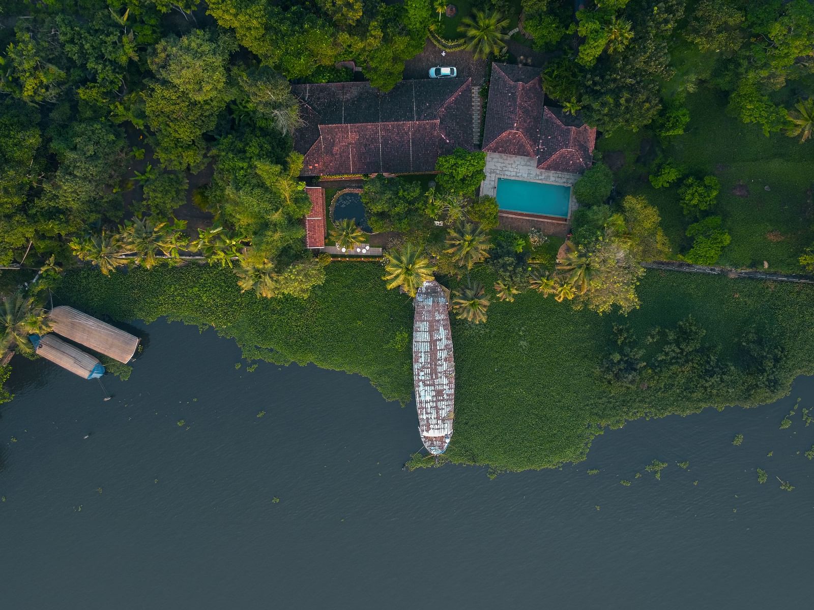 An aerial shot of BluSalzz Villas - Muhamma Resort, Alleppey surrounded by greenery and the Vembanad Lake