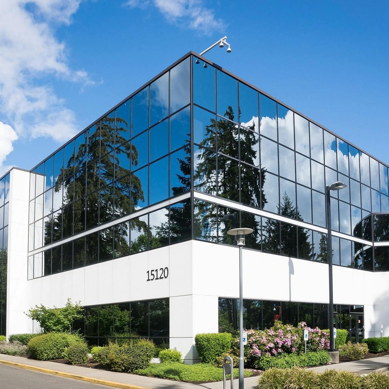 Exterior view of a contemporary office building with reflecting windows under a blue sky.