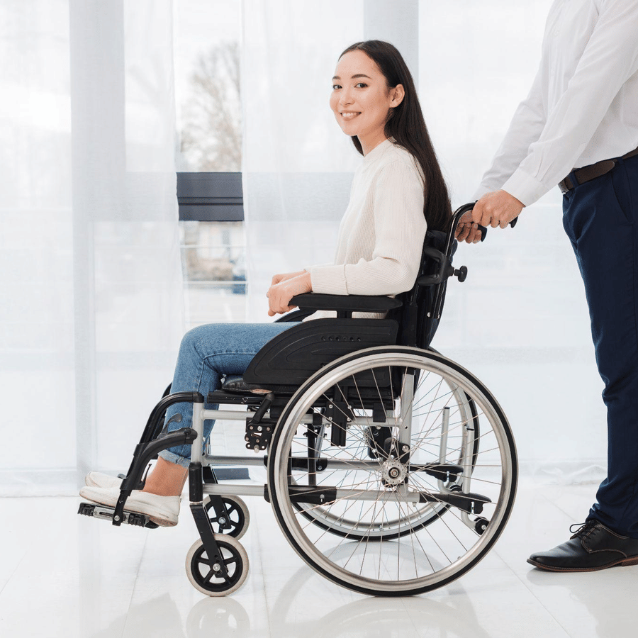 A woman being assisted on a wheelchair by a man.