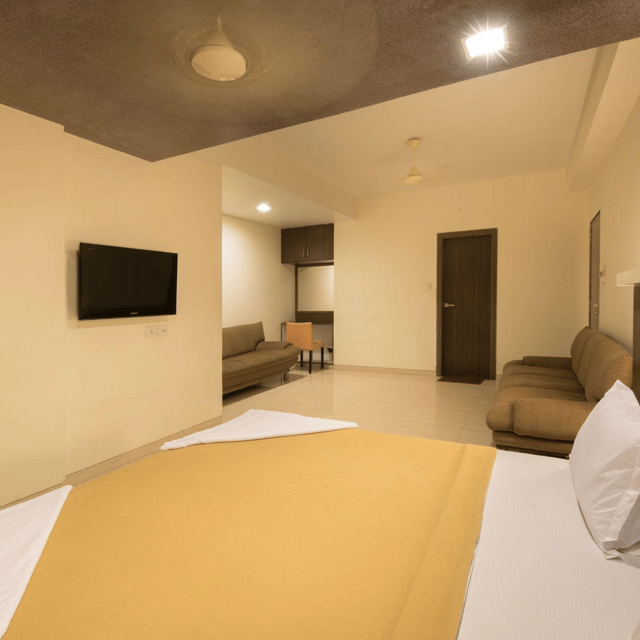 Wide-angle view of a hotel suite showing a large bed in the foreground and a sitting area further back.