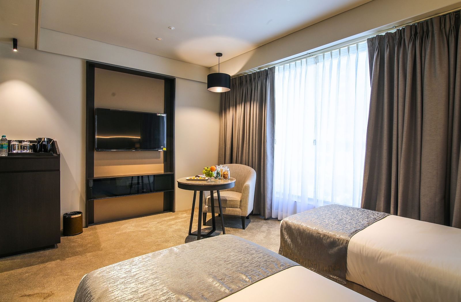 Twin beds with a tv opposite it inside one of the rooms - Essentia Premiere, Pune