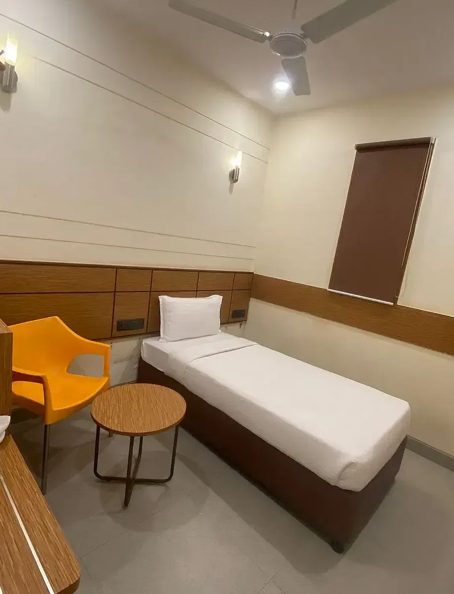 View of a hotel room with a single bed, wooden accents, and warm lighting - Max Hotel Prayagraj