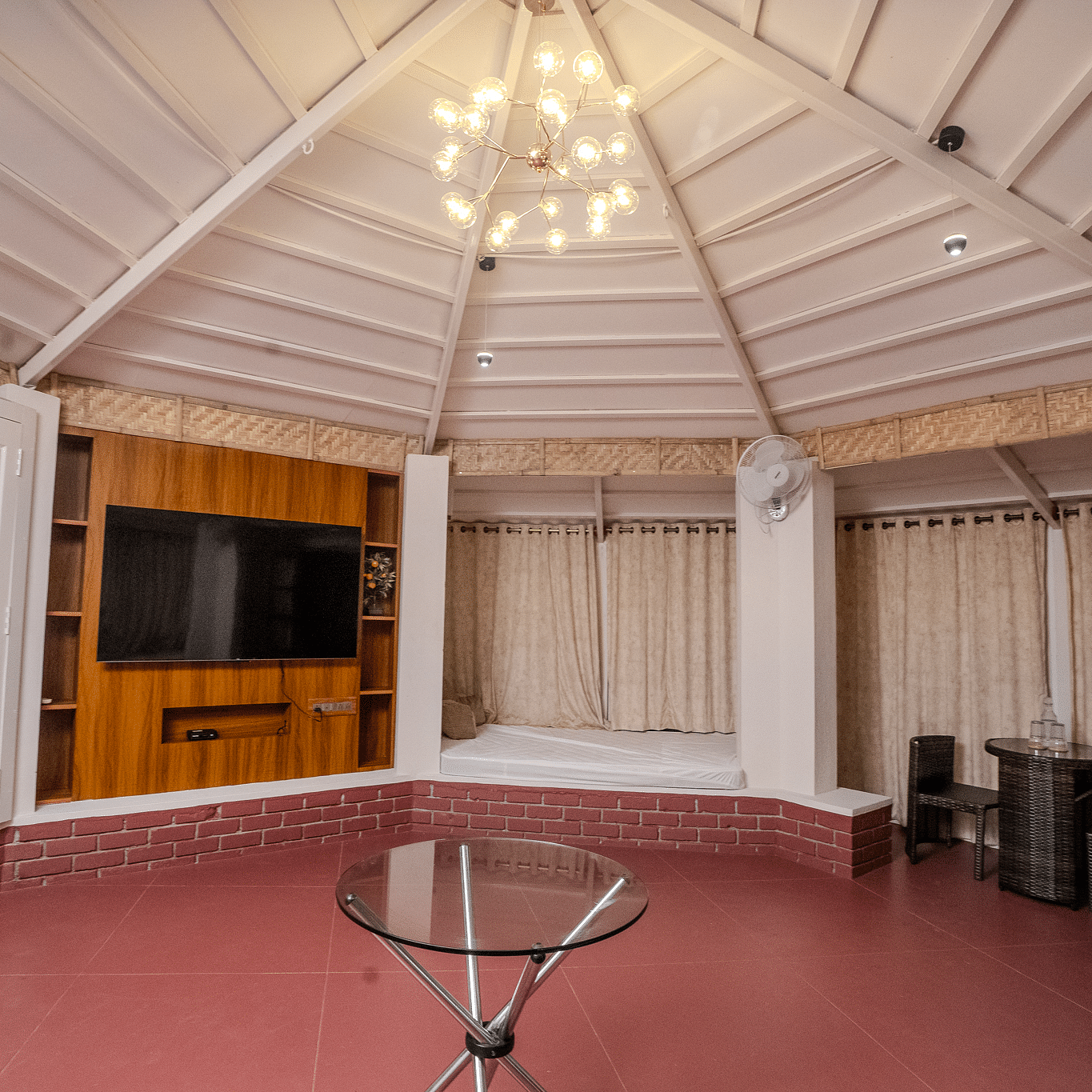 An interior shot of a gazebo that has a TV on the wall and a chandelier with in-built beds | Habba Dates Villa, Hampasandra