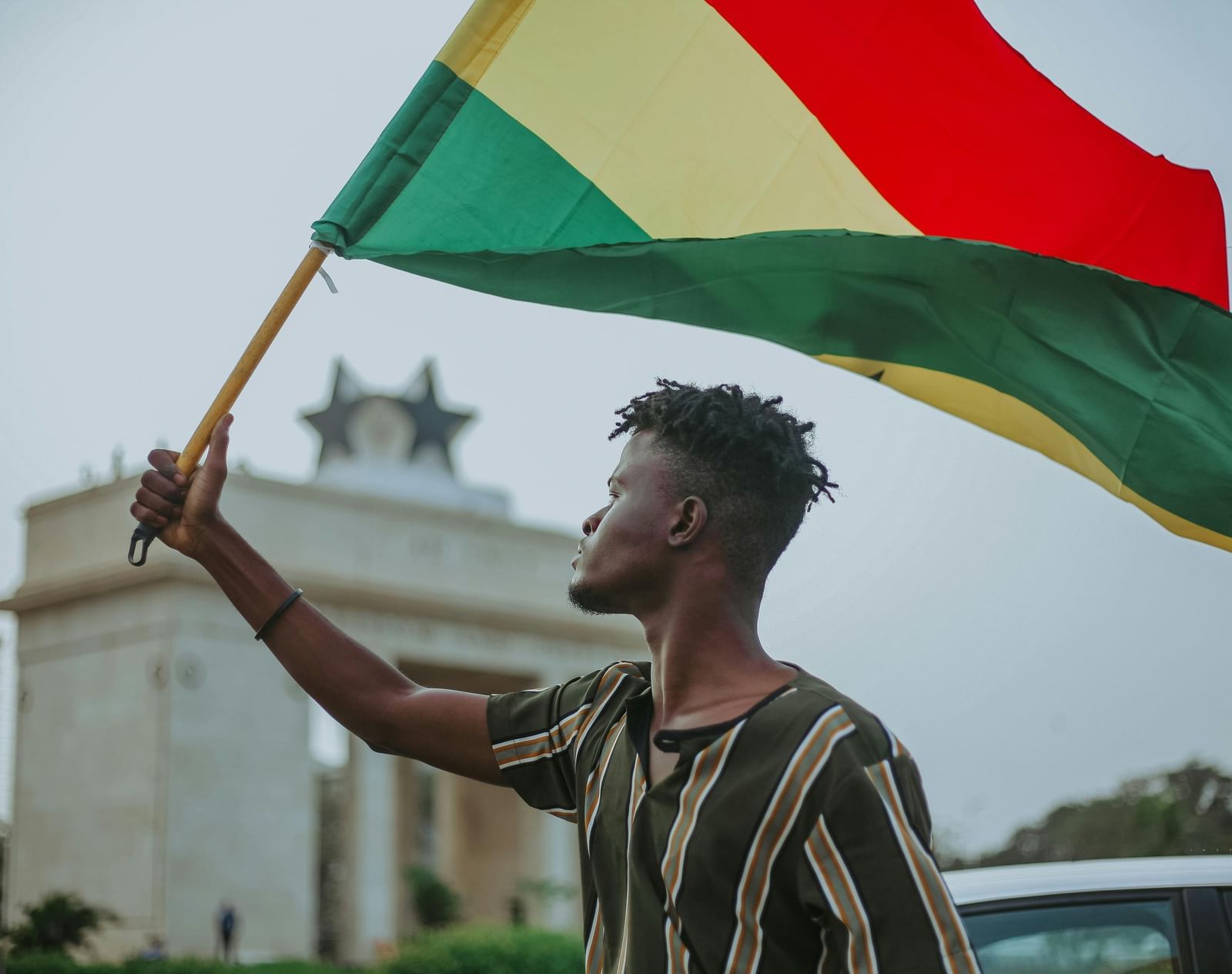 A man waving the Ghanaian flag near Independence Arch.