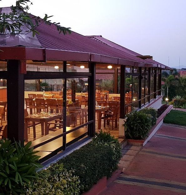 View from outdoor area of a restaurant in a wooden structure and lush greenery | Sheesham Restaurant | Woodstock Resorts, Coorg