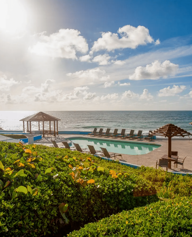 Wooden deck with thatched umbrellas and lounge chairs by the beach | Abaco Inn