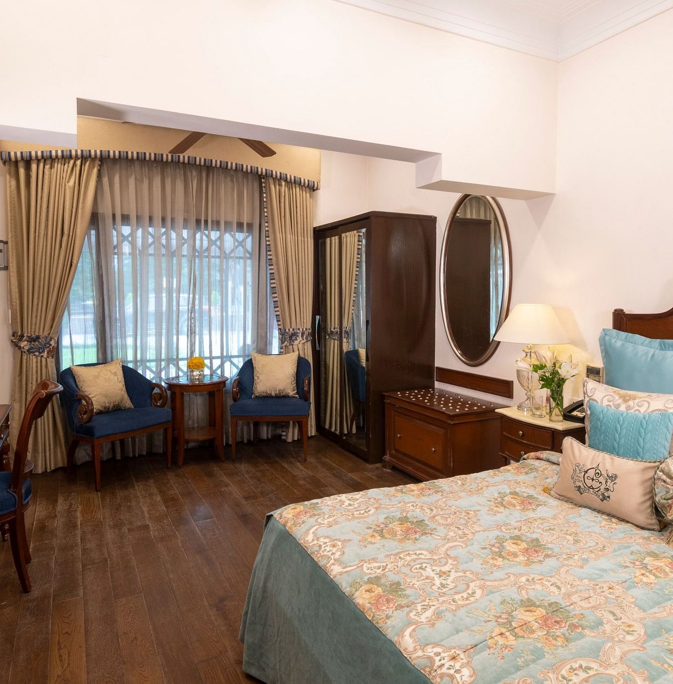 view of the deluxe room with king sized bed with comfortable chairs and a workspace at the Claridges Nabha Residence, Mussoorie