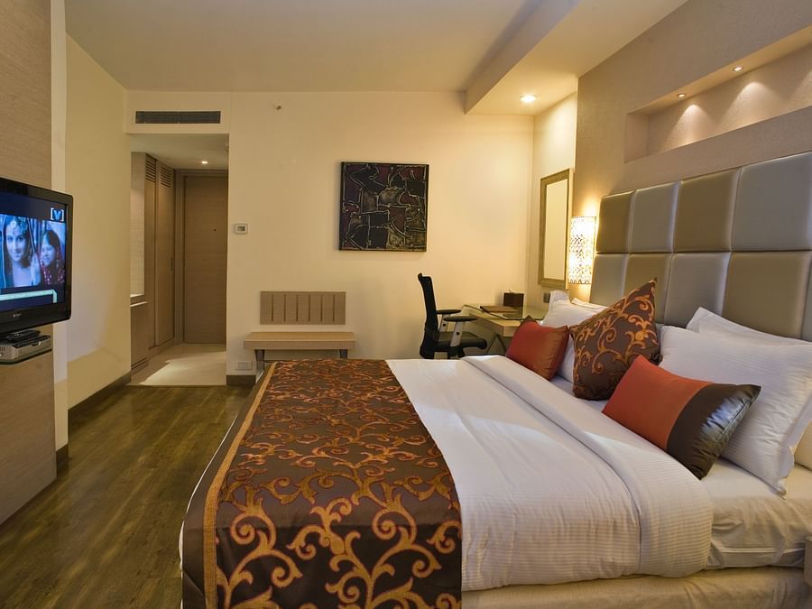 A comfortable hotel room featuring a bed with decorative pillows and a television- The Sonnet, Kolkata