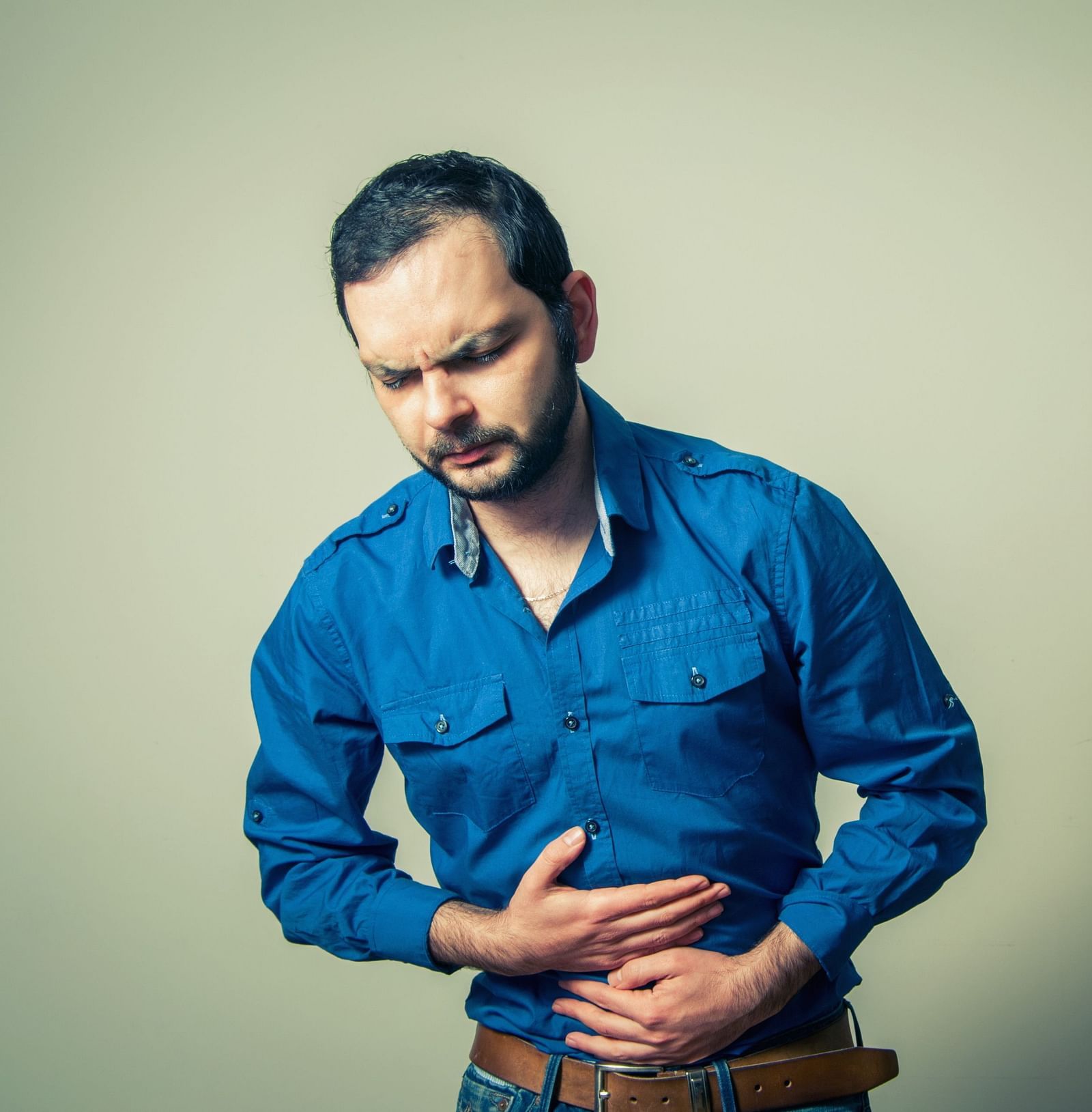 A man clutching his stomach, experiencing an ache - Shreyas Retreat