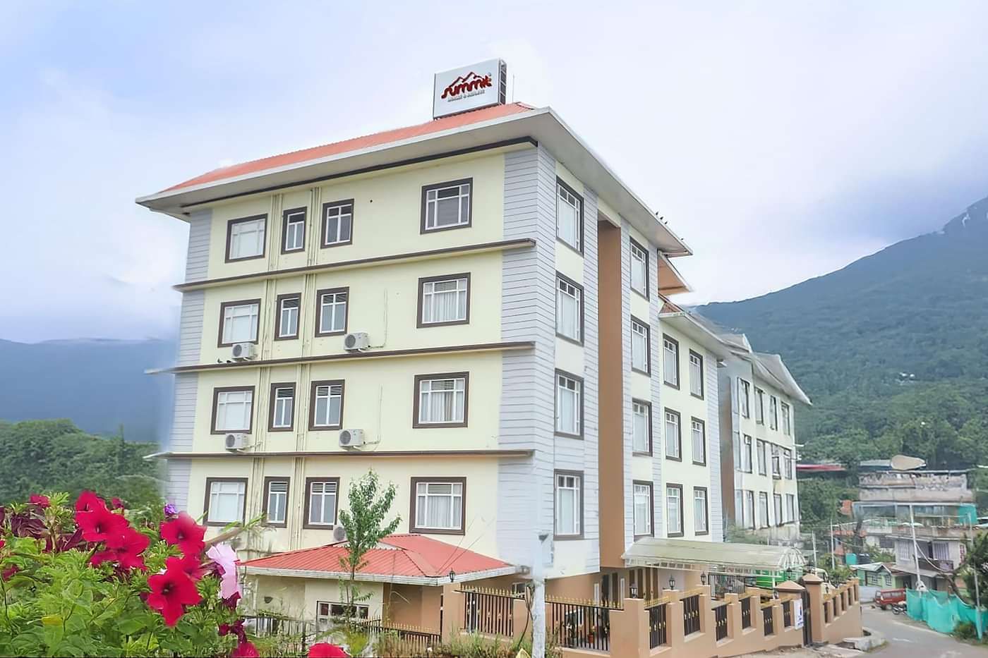 Facade view of Banari Regency by Summit, Namchi, with a dramatic cloudy sky and scenic mountain backdrop