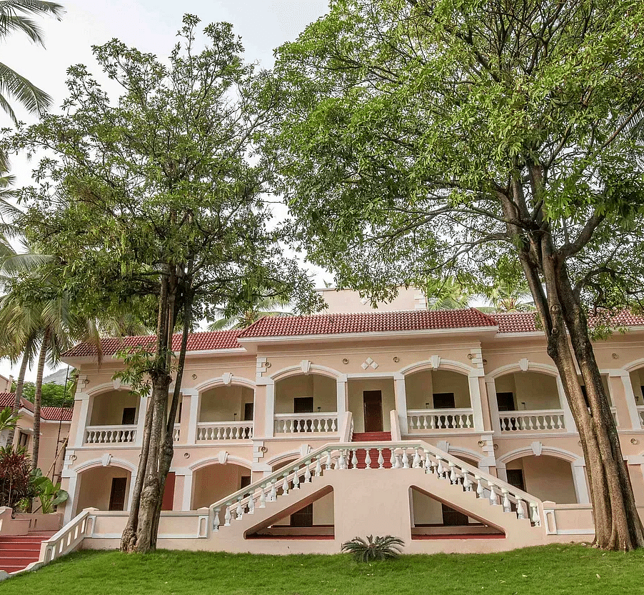 Colonial-style resort building surrounded by tall palm trees and lush green lawns