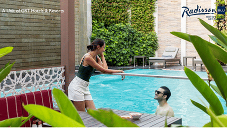 Couple relaxing by the pool at Radisson Blu Hotel & Suites GRT Chennai, highlighting the Urban Escape Offer experience.