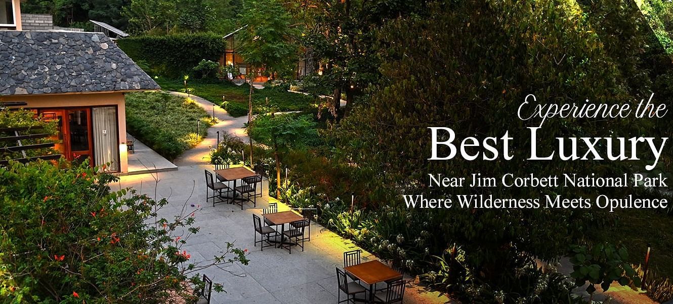 Experience the Best Luxury Near Jim Corbett National Park with an upscale outdoor dining setup surrounded by lush greenery and evening ambience.