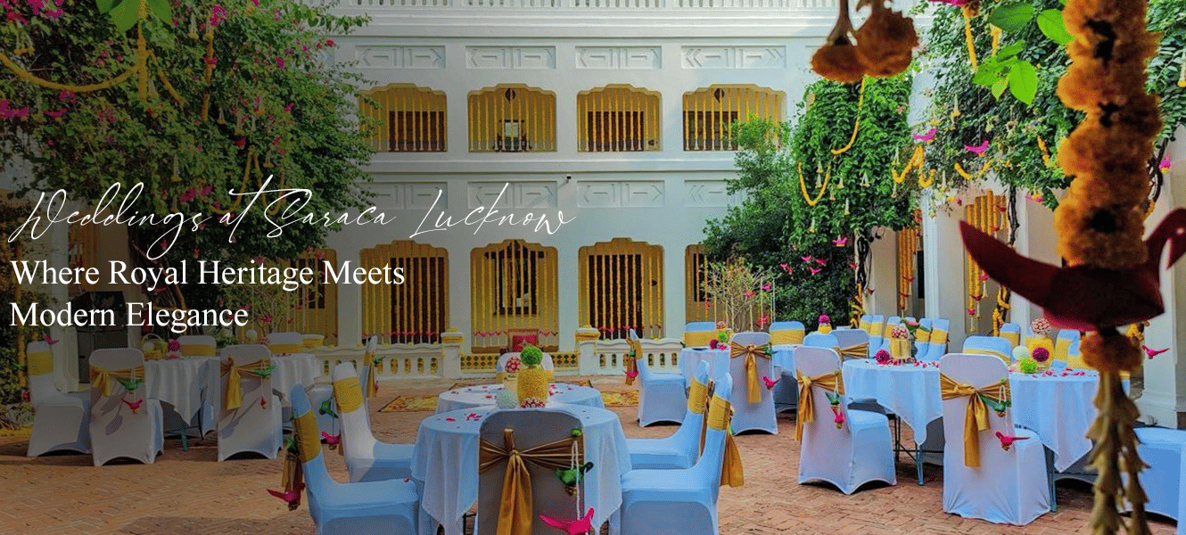 Vibrant courtyard with white columns, hanging greenery, and colourful dining tables arranged for a festive wedding setup at Saraca Lucknow.