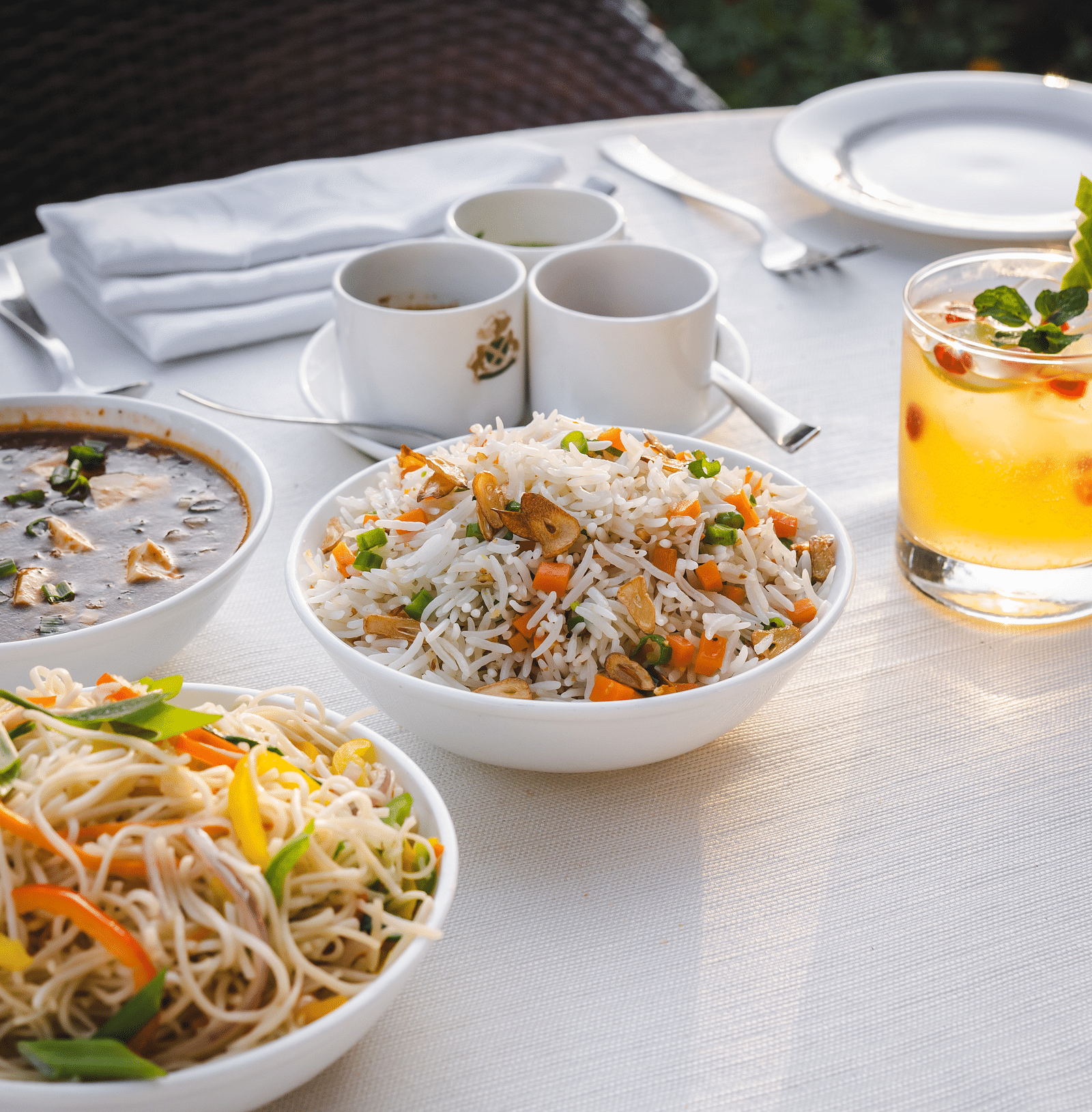 A dining table set with cups and delicious food with a refreshing beverage at The Claridges Nabha Residence