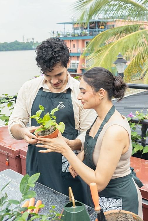 Couple nurturing plants at Polo Floatel Kolkata with a rooftop garden setting.