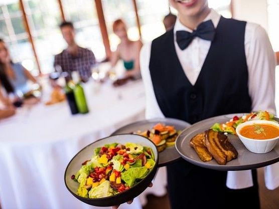 Server holding three plates of food in his hands.