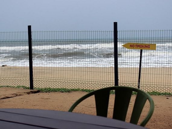 An image of a chair and a table with the backdrop of a beach where waves are hitting the shore