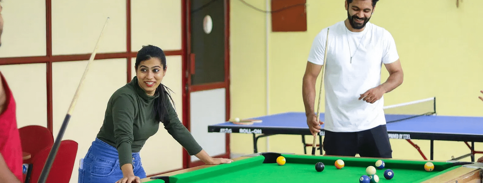 Three people playing pool in a brightly lit yellow room